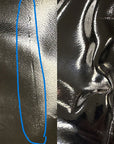Close-up of black over the knee rubber boots by ACQUO of Sweden, highlighting minor surface imperfections and vertical crease lines on the shaft, indicative of the handmade character and material texture of premium high-shine fashion boots.