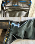 Close-up of ACQUO of Sweden black rubber boot surface with visible wrinkles, creases, and irregular texture imperfections