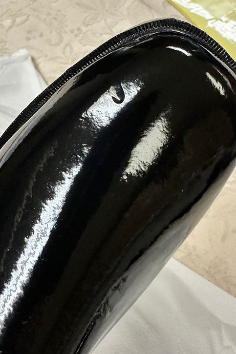 Detailed view of ACQUO of Sweden's black over-the-knee rubber boot, featuring a visible surface mark near the toe area—demonstrating the unique characteristics of handcrafted, high-shine designer footwear