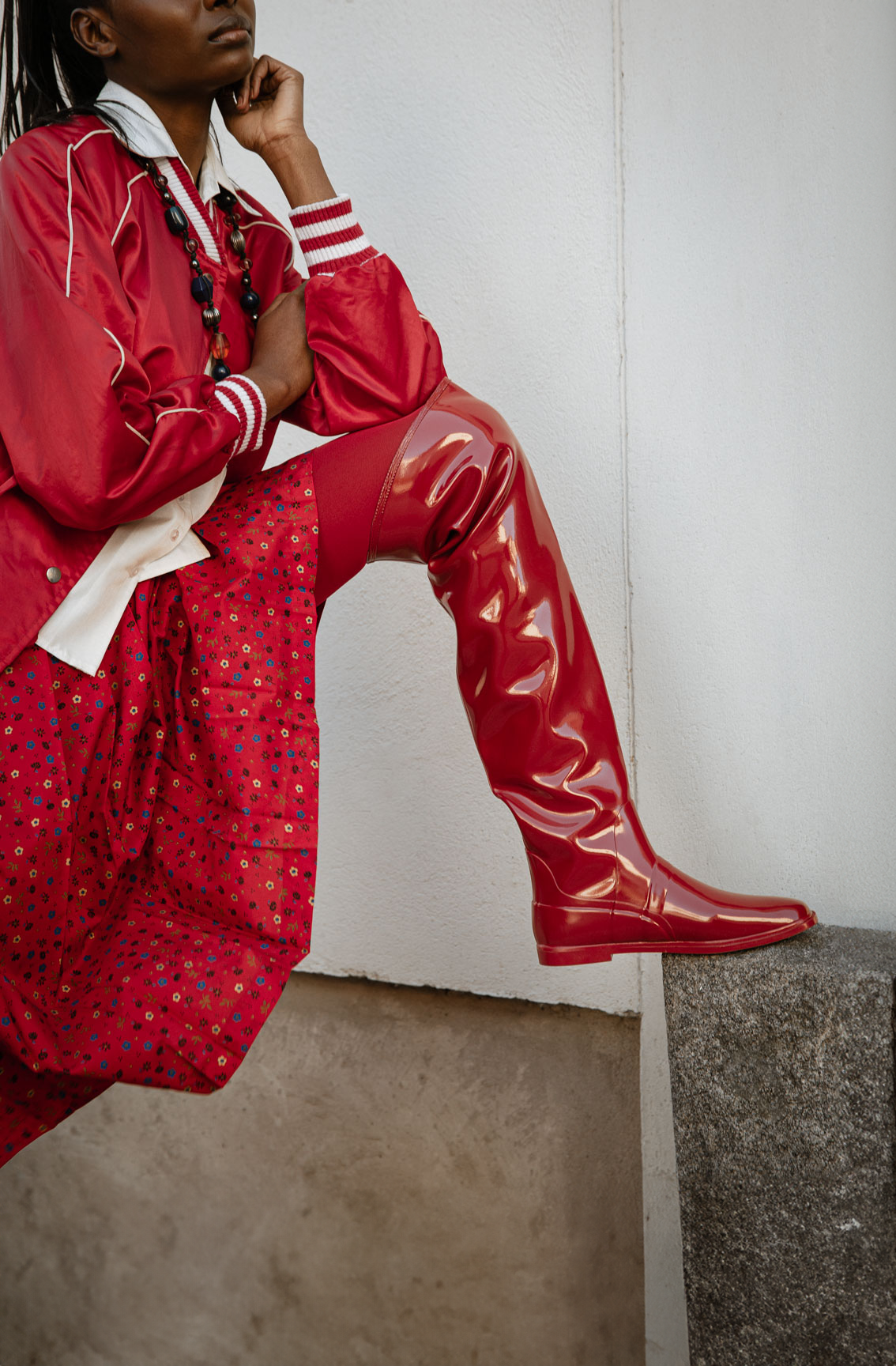 Model wearing Greta Cherry Red over-the-knee boots by ACQUO of Sweden styled with a red patterned dress and satin jacket. Waterproof boots with elegant Swedish design and contemporary Scandinavian fashion inspiration
