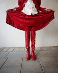 Model wearing Greta Cherry Red over-the-knee boots by ACQUO of Sweden styled with a flowing red skirt and satin jacket. Waterproof boots featuring elegant Swedish design and bold Scandinavian fashion styling