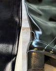Close-up of ACQUO of Sweden black rubber boot surface with visible creases and uneven texture on the shaft and heel