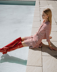Model relaxing by a pool wearing Lisa Cherry Red over-the-knee boots by ACQUO of Sweden with a textured striped dress. Waterproof statement boots featuring elegant Swedish design and contemporary Scandinavian style.