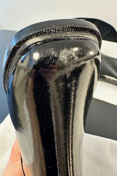 Close-up of the heel and toe area of an ACQUO of Sweden black rubber boot, showing a visible scuff mark on the toe and textured surface on the heel for detailed quality inspection