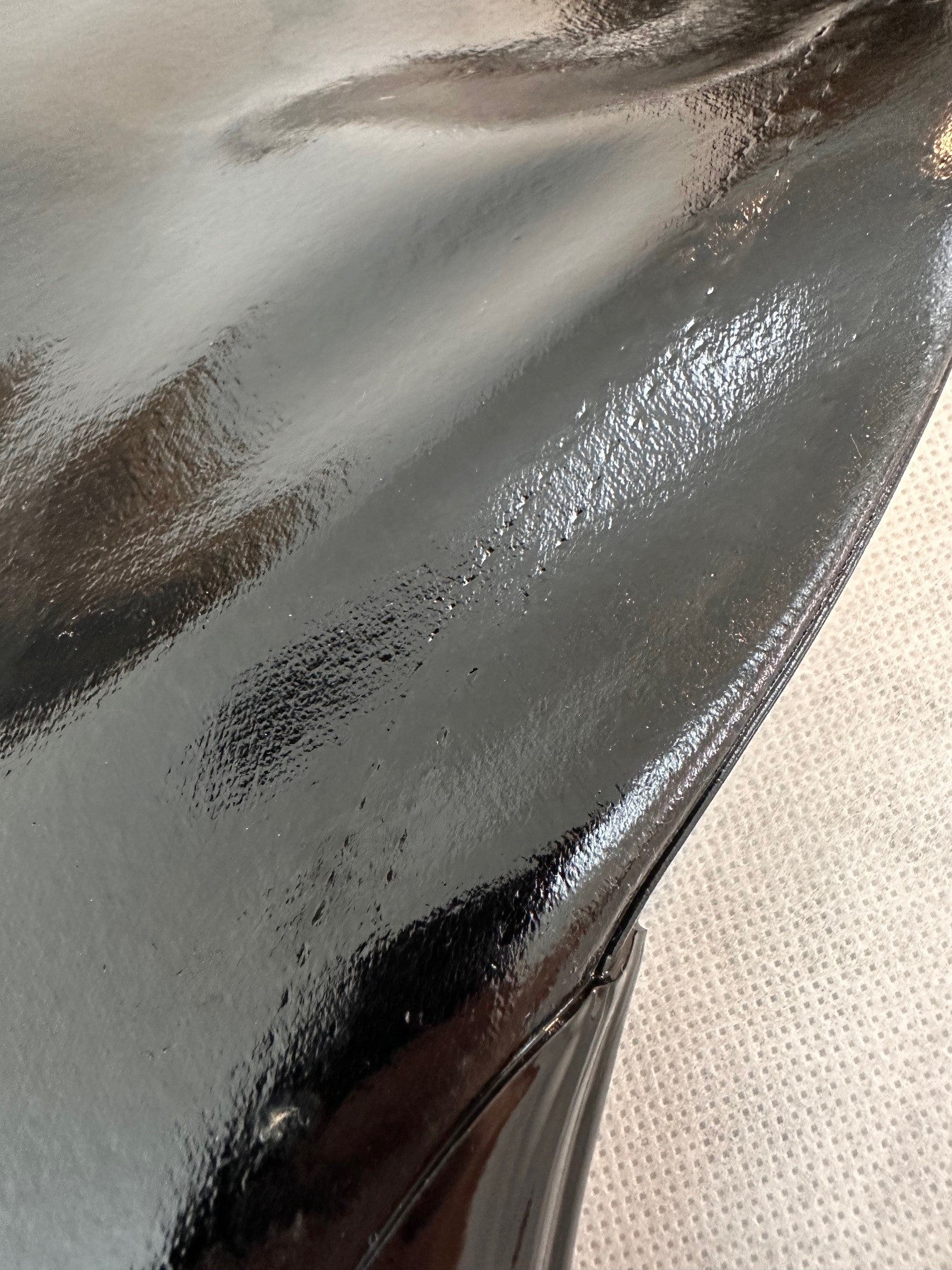 Close-up of ACQUO of Sweden's black rubber boot showing a minor surface imperfection, highlighting the high-shine texture and craftsmanship of the material used in their signature over the knee fashion boots