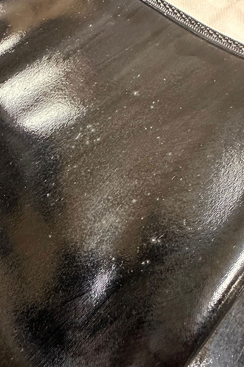 Close-up of ACQUO of Sweden black rubber boot surface with visible spots, bubbles, and uneven texture imperfections