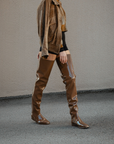 Woman walking in Vega Walnut Brown over-the-knee boots by ACQUO of Sweden styled with black shorts and a brown jacket. Waterproof boots with elegant Swedish design and modern Scandinavian fashion aesthetics